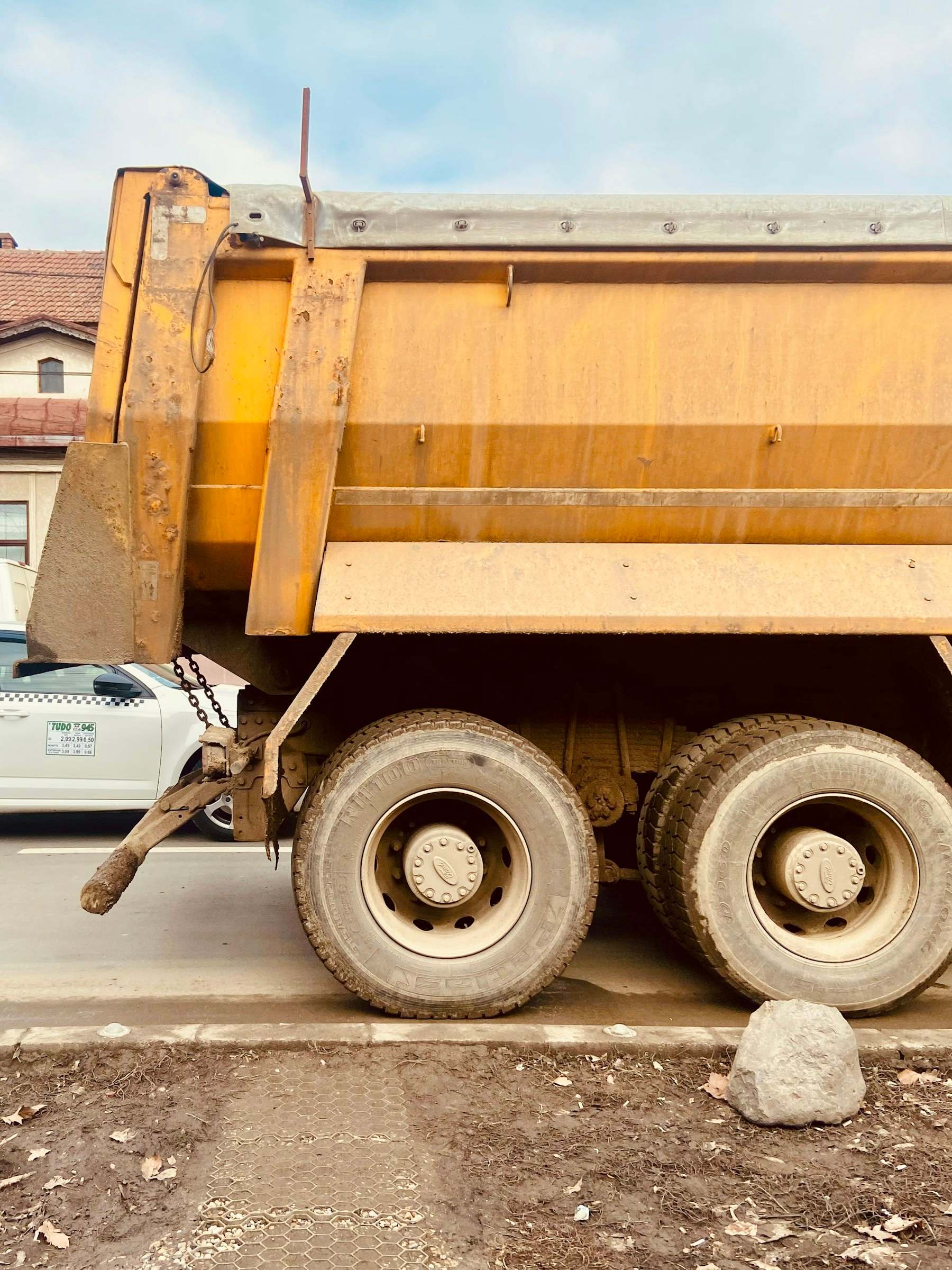 A dump truck parked at a curb next to a construction site