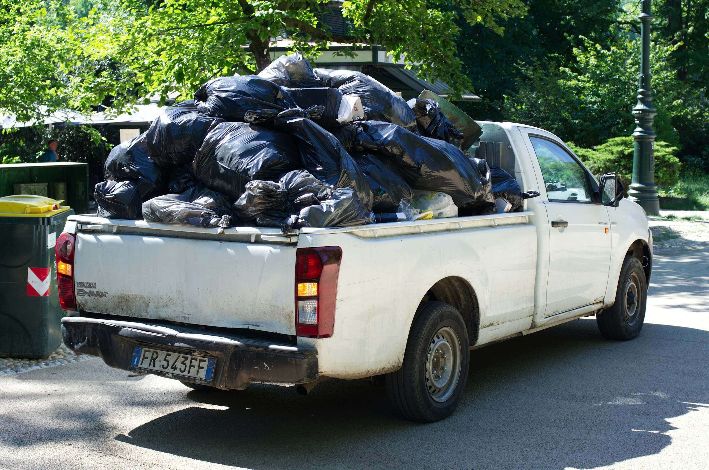 A pickup truck bed piled high with black trash bags