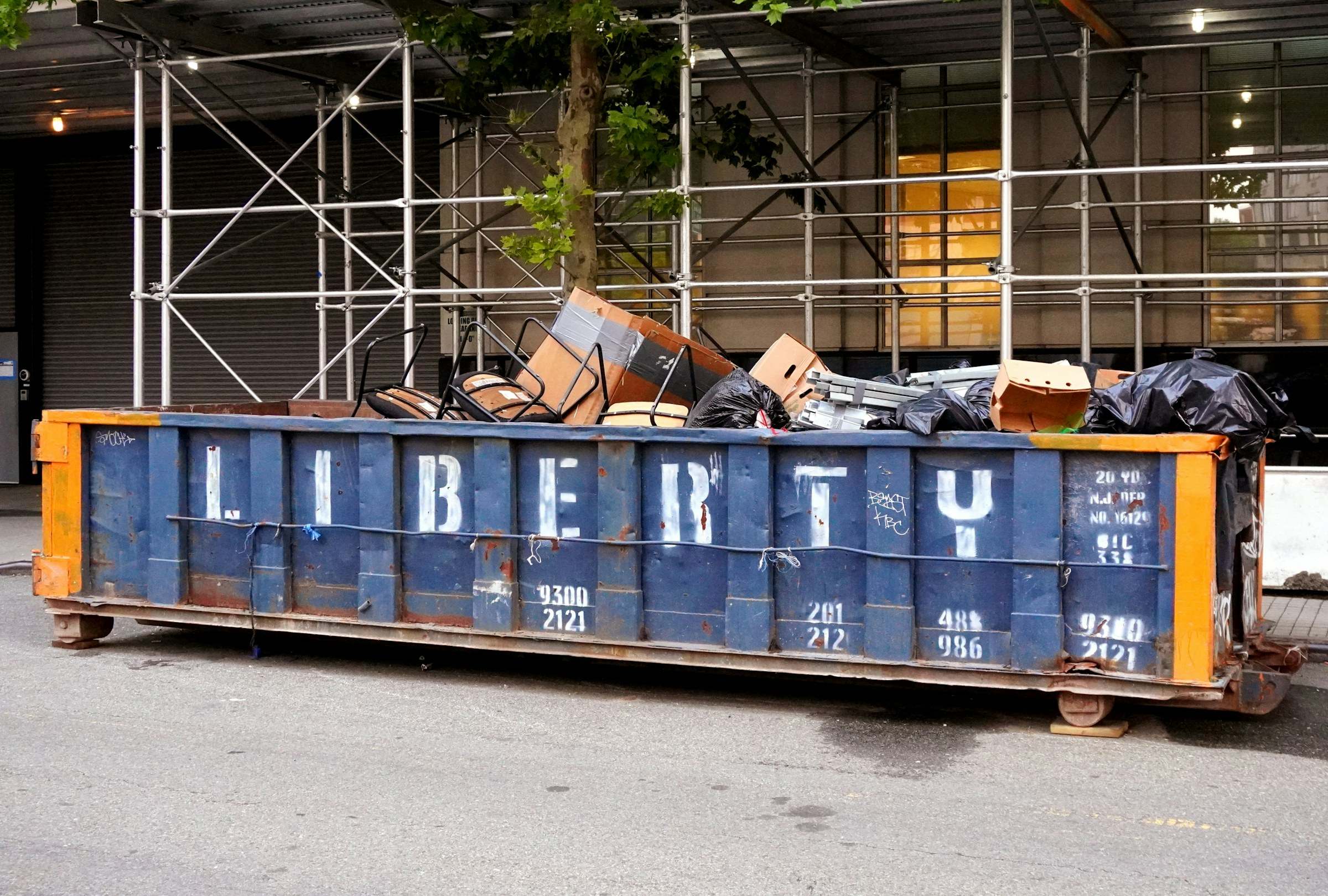 A loaded roll-off dumpster parked at a city curb